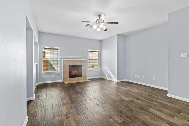 a view of an empty room with wooden floor fireplace and a window