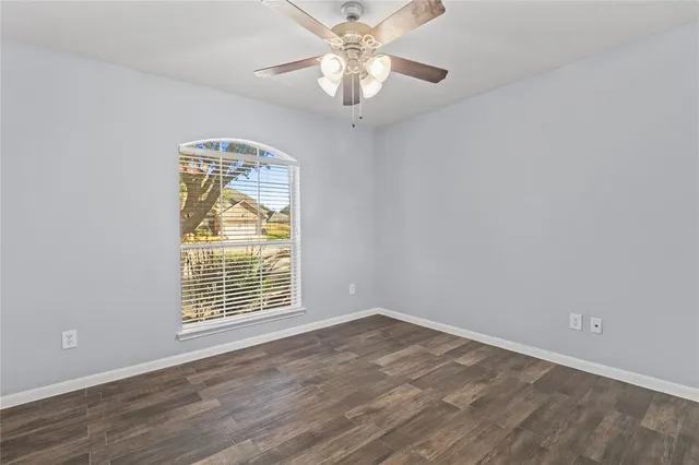 a view of an empty room with a window and wooden floor