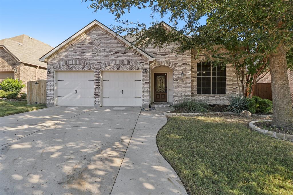 View of front of home with brick siding, driveway, and an attached garage