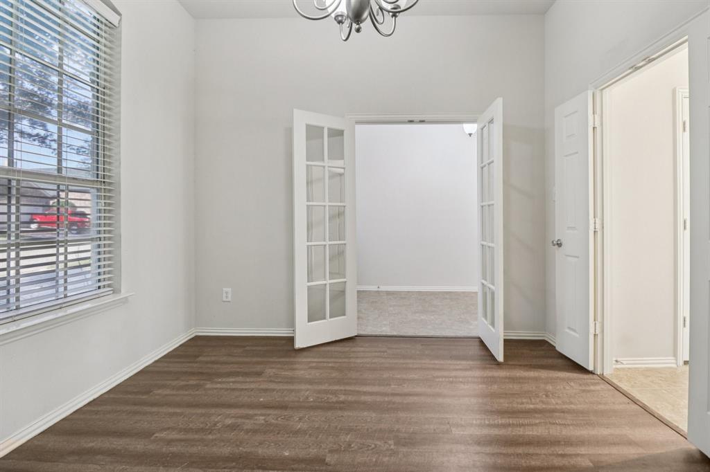 588 Louder Way Fate, TX 75087 - Photo 13 of 34 Unfurnished dining area with french doors, dark wood-style flooring, and a chandelier