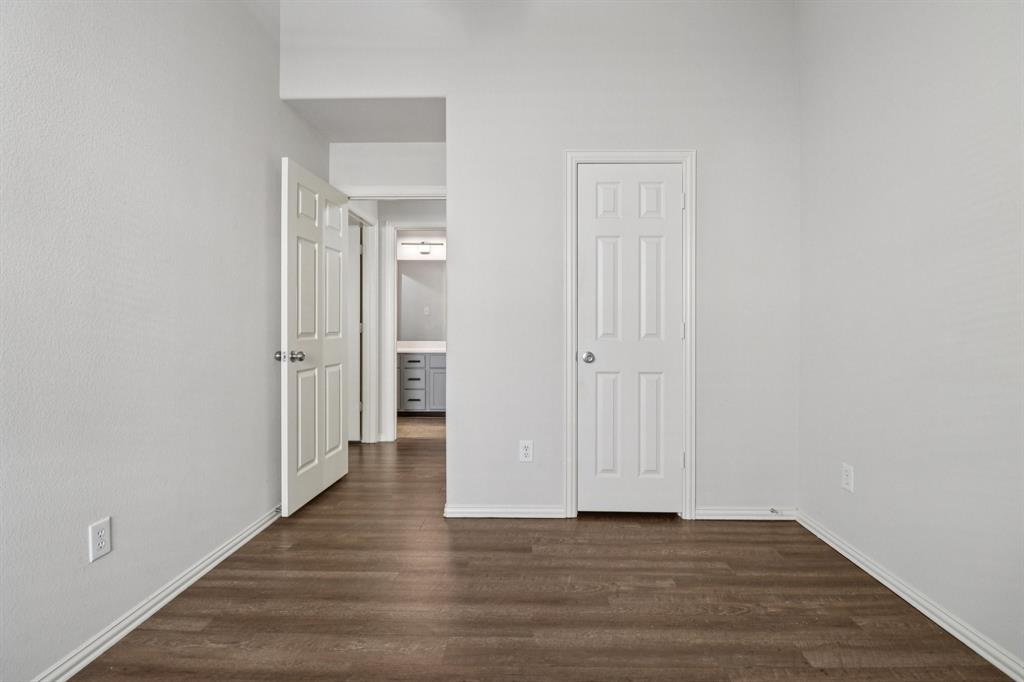 588 Louder Way Fate, TX 75087 - Photo 30 of 34 Unfurnished bedroom featuring dark wood-style floors and a closet
