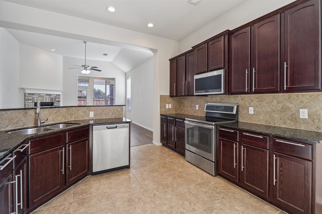 588 Louder Way Fate, TX 75087 - Photo 9 of 34 Kitchen featuring appliances with stainless steel finishes, decorative backsplash, dark stone counters, lofted ceiling, and ceiling fan