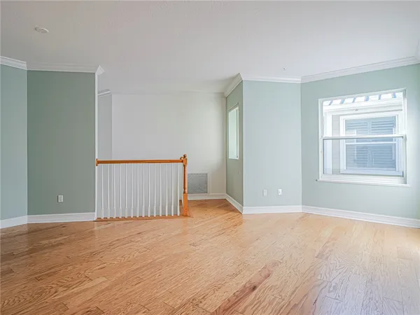an empty room with wooden floor cabinet and windows