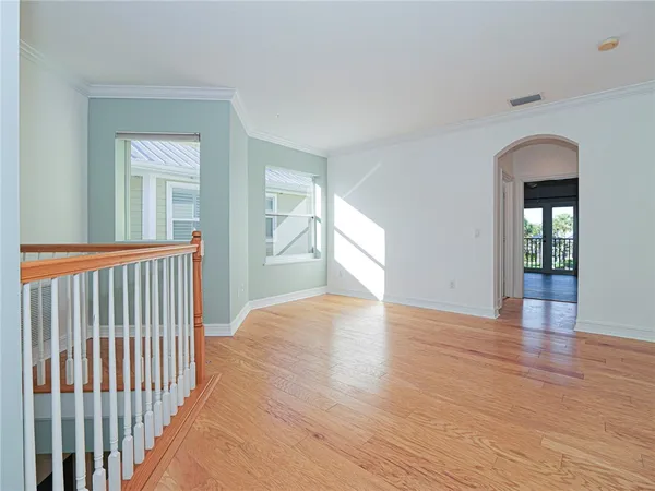 a view of empty room with wooden floor and fan