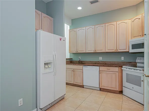 a kitchen with granite countertop white cabinets and white appliances