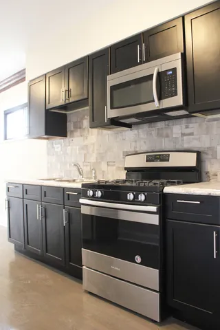 a kitchen with stainless steel appliances granite countertop wooden cabinets microwave and stove