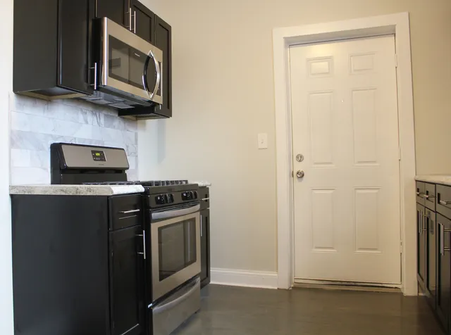 a kitchen with stainless steel appliances granite countertop white cabinets and a stove top oven