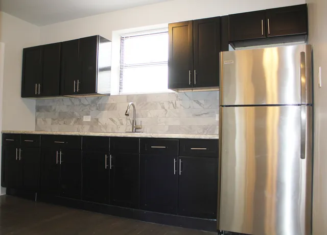 a kitchen with granite countertop white cabinets and refrigerator