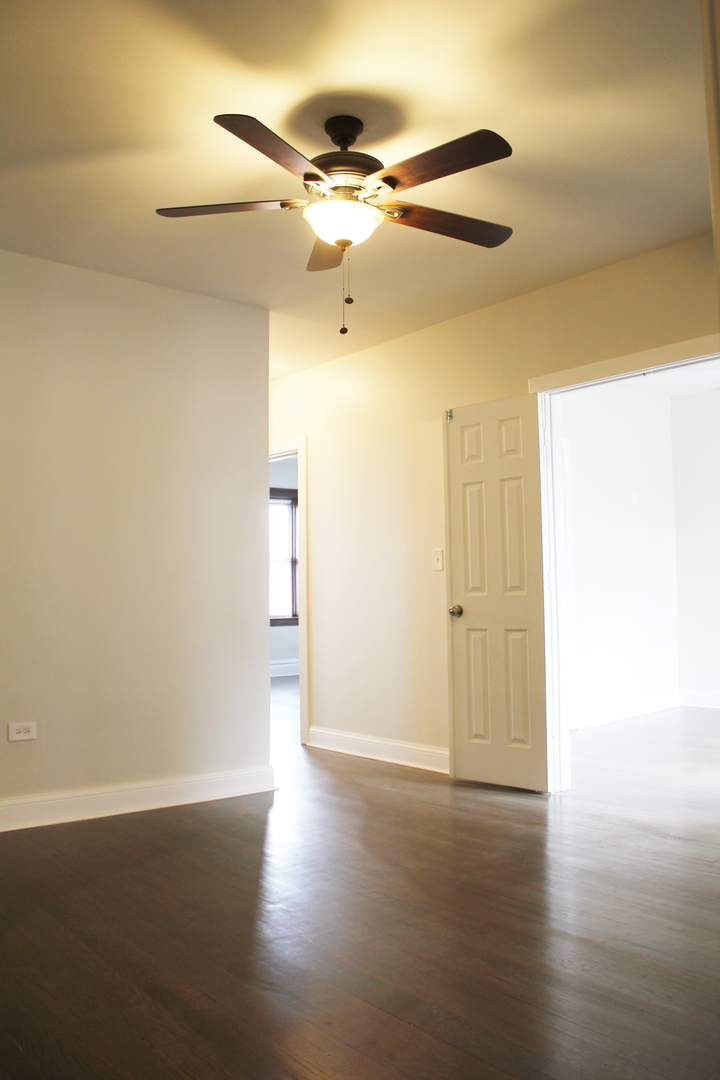 6 West 111th Place Chicago, IL 60628 - Photo 9 of 18 an empty room with wooden floor fan and windows