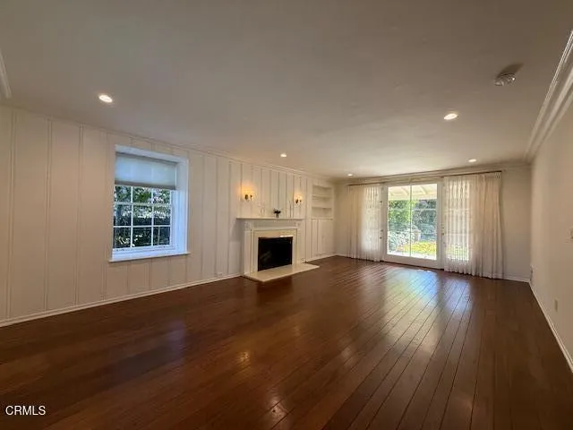an empty room with wooden floor fireplace and windows