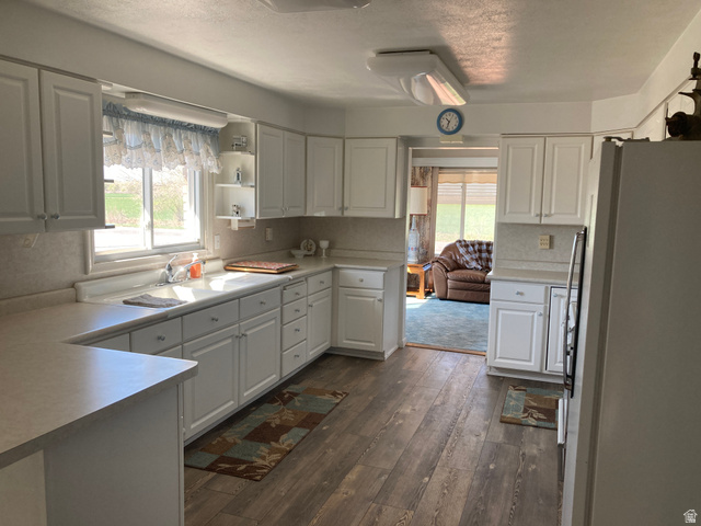 200 South 2800th Street West Ogden, UT 84404 - Photo 6 of 42 Kitchen with freestanding refrigerator, dark wood-type flooring, light countertops, white cabinets, and a textured ceiling