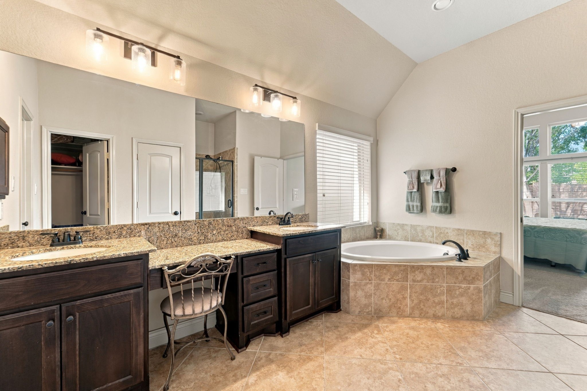 9818 Reston Ranch Court Cypress, TX 77433 - Photo 15 of 38 Designed for everyday comfort, this bathroom includes ample cabinet storage, and a corner soaking tub with natural light from the nearby window, making it a true retreat within the primary suite.