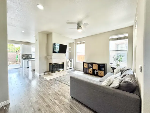 a living room with furniture a fireplace a flat screen tv and wooden floor