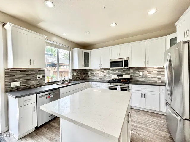 a kitchen with granite countertop white cabinets and stainless steel appliances