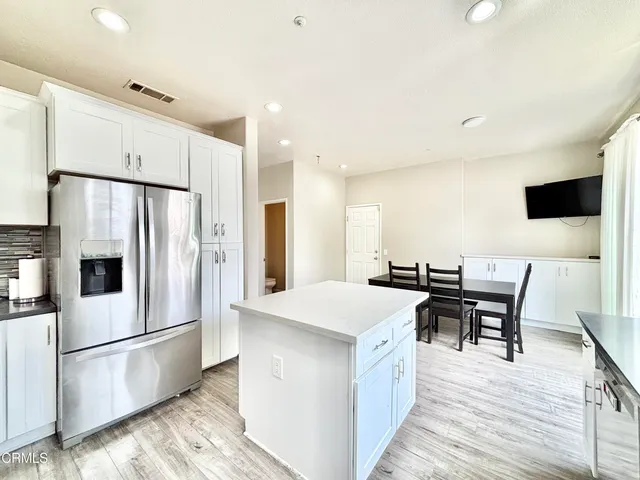 a kitchen with stainless steel appliances a stove a refrigerator a dining table and chairs with wooden floor