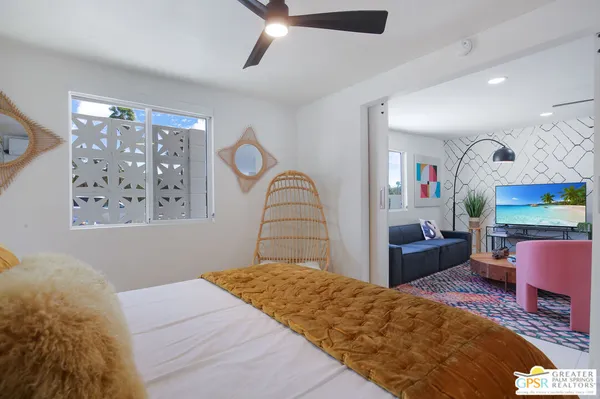 a bedroom with a bed large window with table and chair