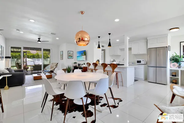 a view of a dining room and livingroom with furniture a rug a painting and a chandelier