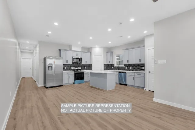 a large kitchen with a large counter top stainless steel appliances and cabinets