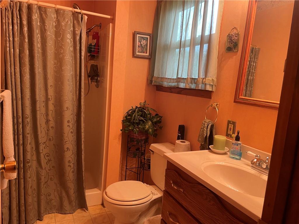 1606 Atkinson Street New Castle, PA 16101 - Photo 12 of 15 a bathroom with a sink a toilet a mirror and shower curtain