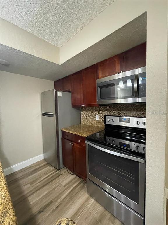 5148 Conroy Road, Unit 18 Orlando, FL 32811 - Photo 20 of 30 a kitchen with wooden cabinets and stainless steel appliances