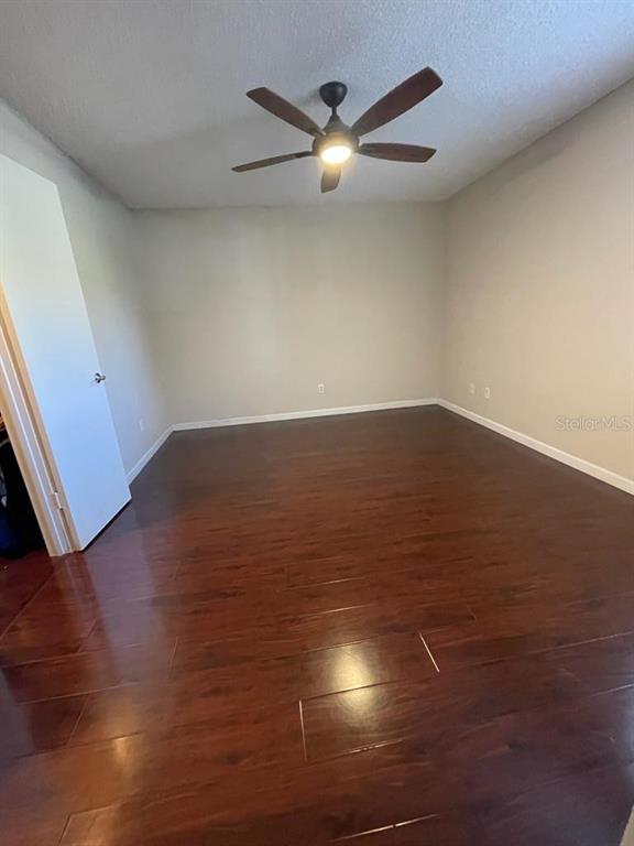 5148 Conroy Road, Unit 18 Orlando, FL 32811 - Photo 5 of 30 a view of an empty room with wooden floor and a ceiling fan