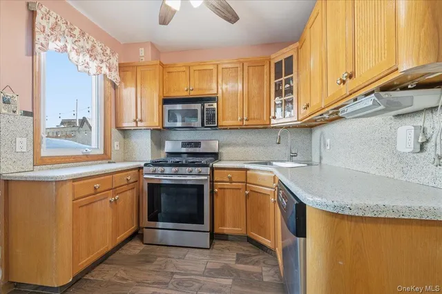 a kitchen with stainless steel appliances granite countertop wooden cabinets a stove a sink and a microwave
