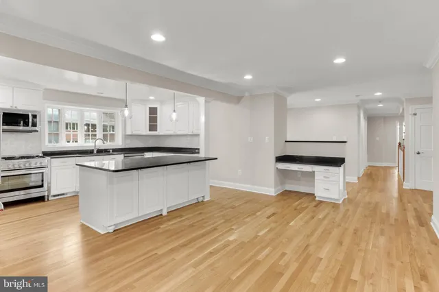a kitchen with granite countertop a refrigerator a sink and white cabinets