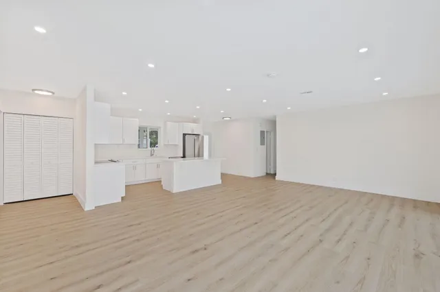 a view of a kitchen with white cabinets and wooden floor