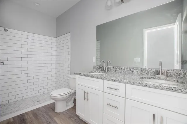 a bathroom with a granite countertop toilet a sink and a mirror