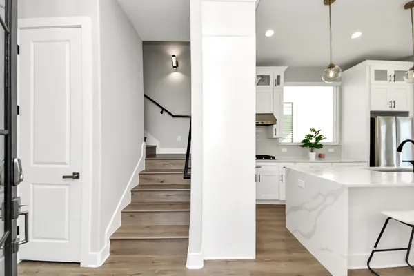 a kitchen with stainless steel appliances kitchen island granite countertop a refrigerator a sink dishwasher a stove and a dining table with wooden floor