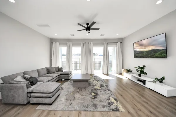 a large kitchen with kitchen island a stove a sink a refrigerator and a dining table with wooden floor