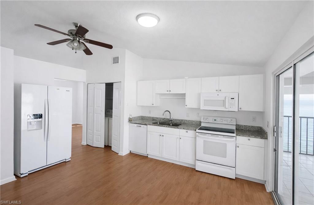 5424 16th Place Southwest, Unit C3 Naples, FL 34116 - Photo 3 of 7 a kitchen with white cabinets and white appliances
