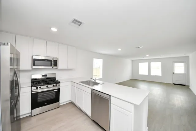 a kitchen with granite countertop a sink stainless steel appliances and cabinets