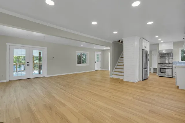 a view of an empty room with a window and wooden floor