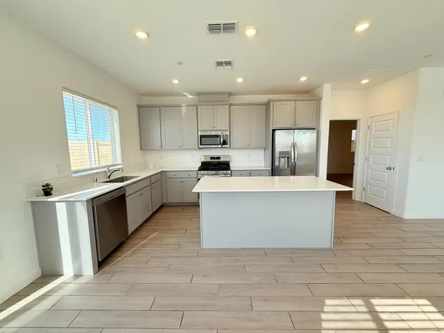 a large kitchen with stainless steel appliances kitchen island granite countertop a stove a sink a refrigerator and white cabinets