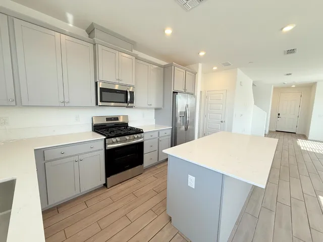 a kitchen with stainless steel appliances kitchen island sink refrigerator and cabinets