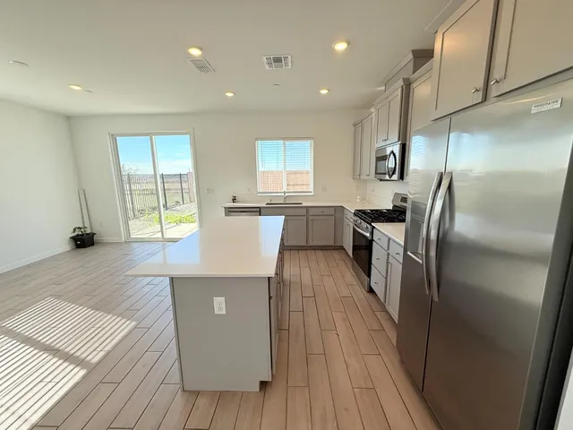 an open kitchen with wooden floor and refrigerator