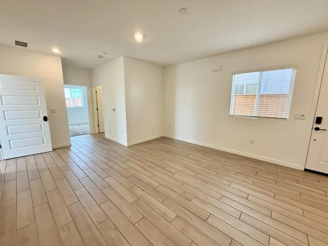 a view of an empty room with wooden floor and a window