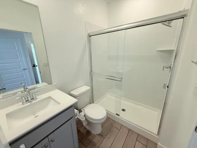 a bathroom with a granite countertop sink toilet a mirror and shower