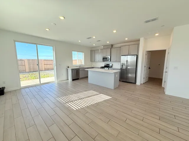 a large white kitchen with stainless steel appliances granite countertop a stove a refrigerator a sink dishwasher and a oven with wooden floor