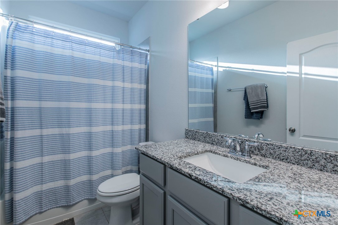 908 Coriander Road Temple, TX 76501 - Photo 16 of 28 a bathroom with a granite countertop sink a toilet and a mirror