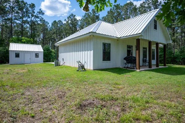 a view of a house with a yard potted plants and a large tree
