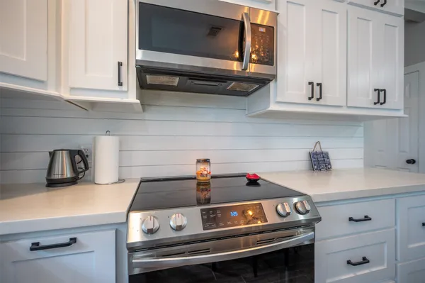a kitchen with stainless steel appliances white cabinets and wooden floor