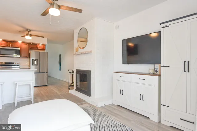 a living room with stainless steel appliances furniture a flat screen tv and kitchen view