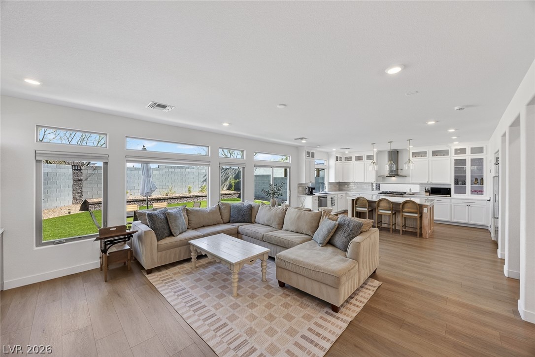 10446 Emerald Rye Street Las Vegas, NV 89183 - Photo 36 of 37 An open floorplan seamlessly connects the well-lit living area to a modern kitchen, boasting high ceilings and rich wood flooring throughout.