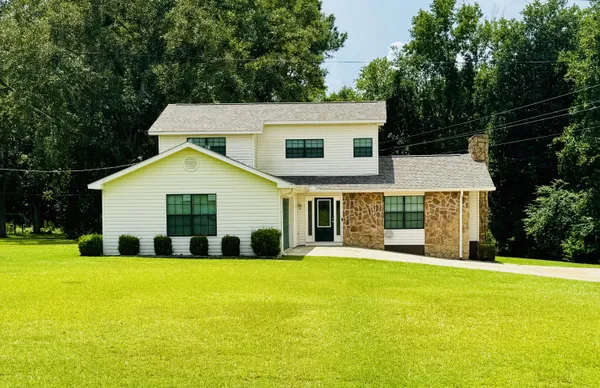 a view of house with yard and trees in the background