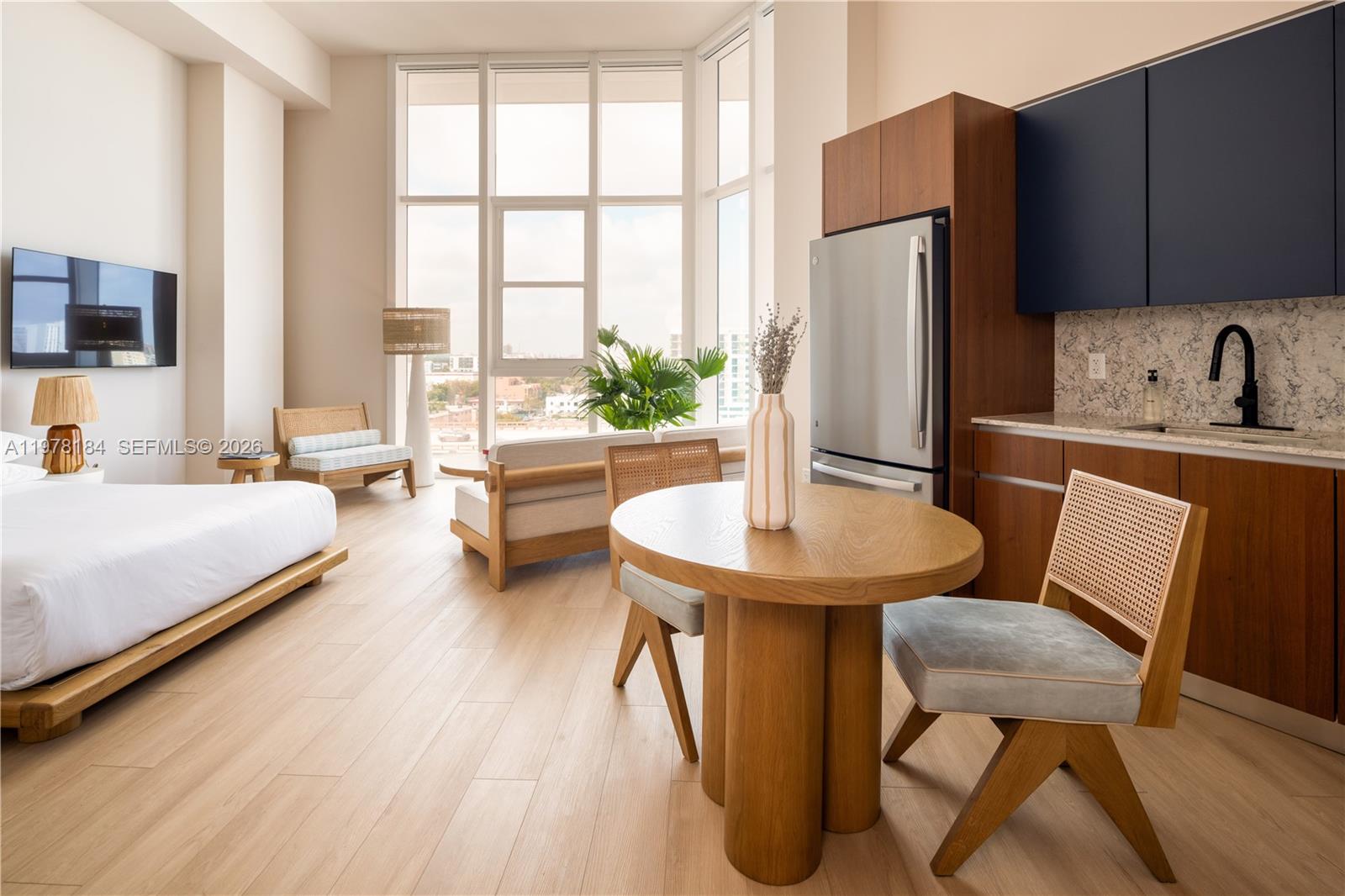 a living room with stainless steel appliances furniture a refrigerator and a table