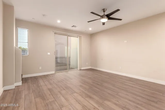 an empty room with wooden floor and a ceiling fan