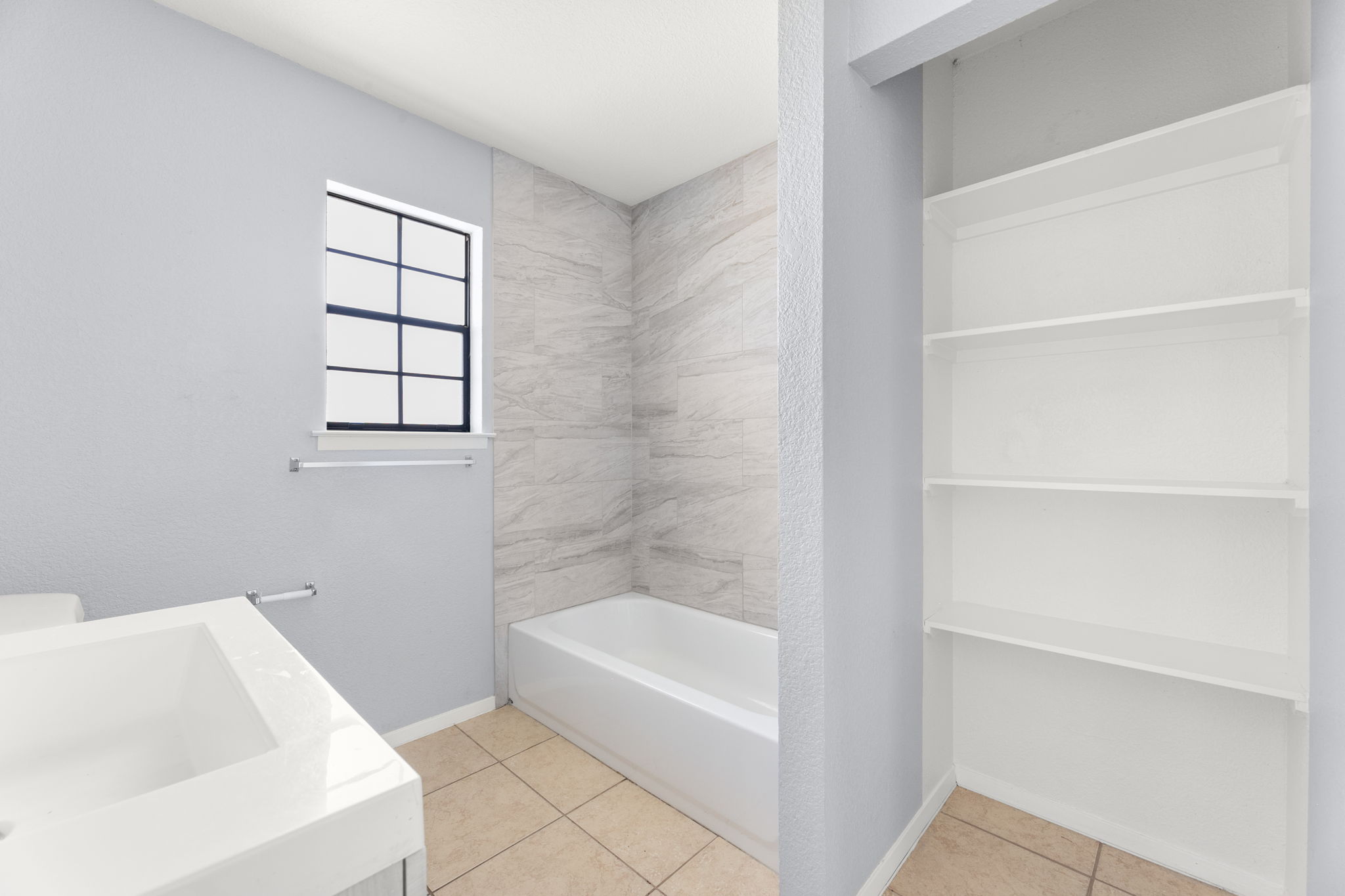 3802 Foust Trail, Unit A Georgetown, TX 78628 - Photo 20 of 34 A pristine bathroom features built-in shelving, a full-size tub, and a window for natural light.