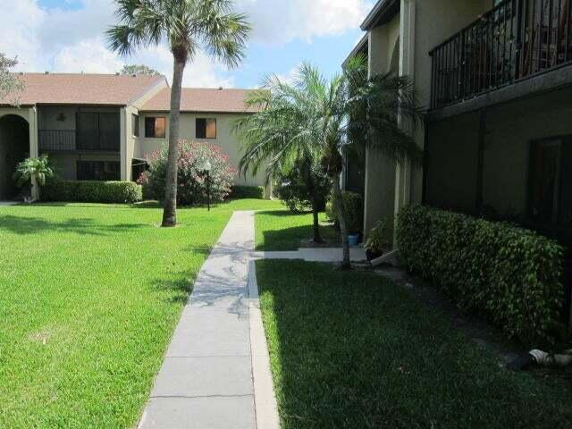 533 Shady Pine Way, Unit B1 Greenacres, FL 33415 - Photo 10 of 19 a front view of a house with a garden and yard